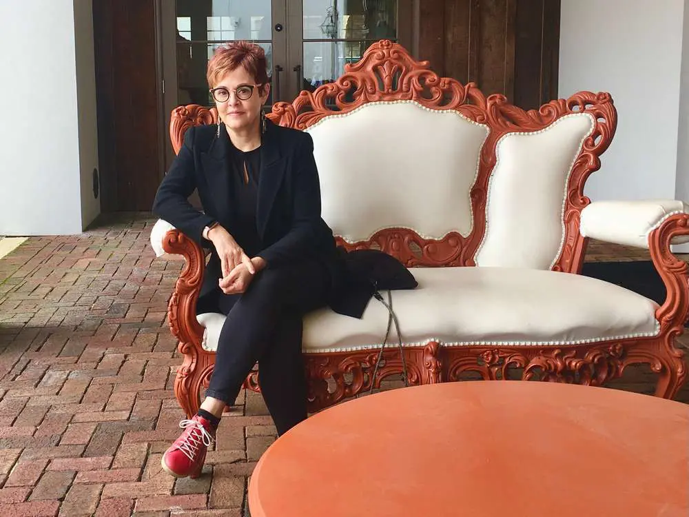 A woman sitting on top of a couch in front of an orange chair.