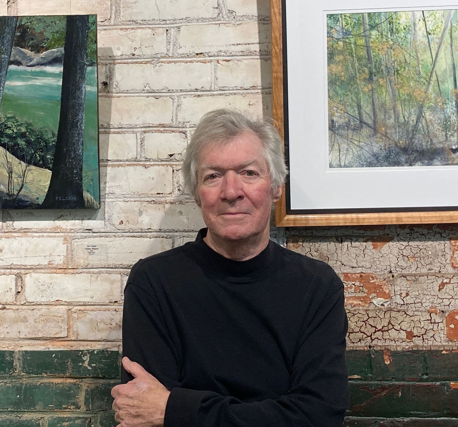 A man standing in front of two paintings.