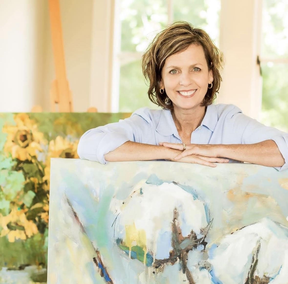 A woman sitting in front of an art work.