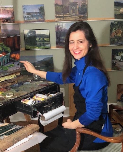 A woman in blue shirt painting on top of table.