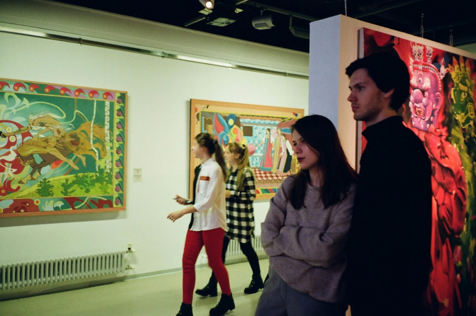 A group of people standing in front of paintings.