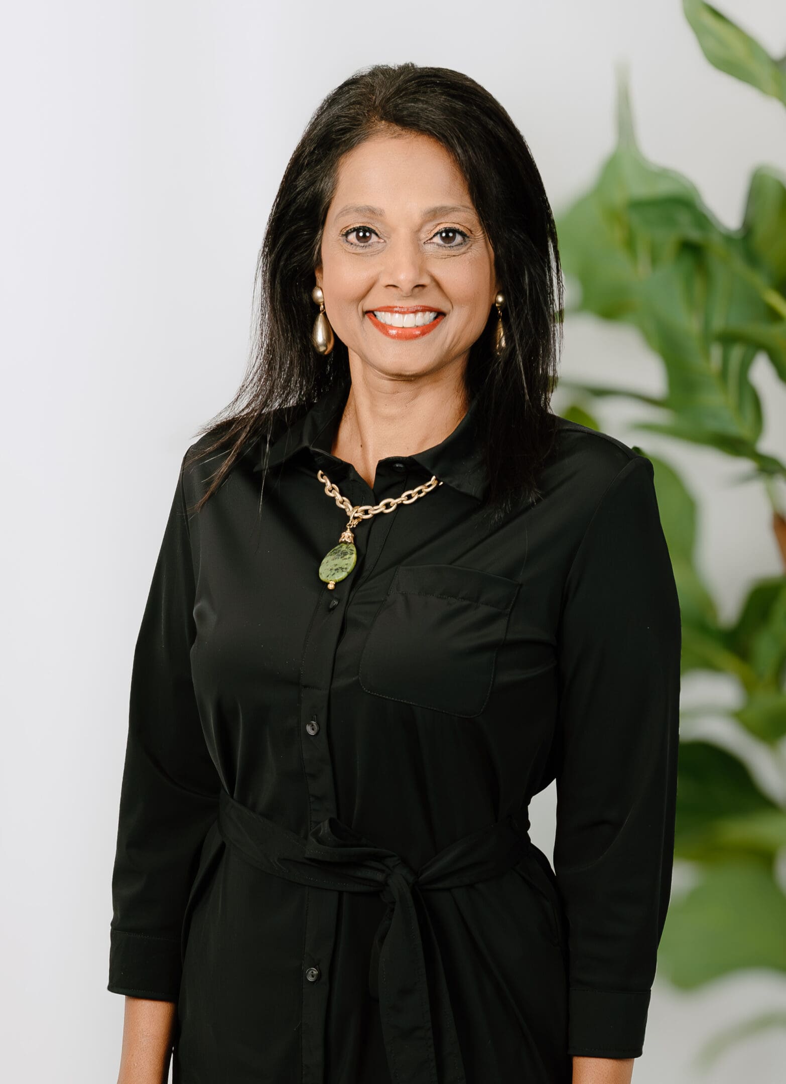 A woman in black shirt standing next to green plant.